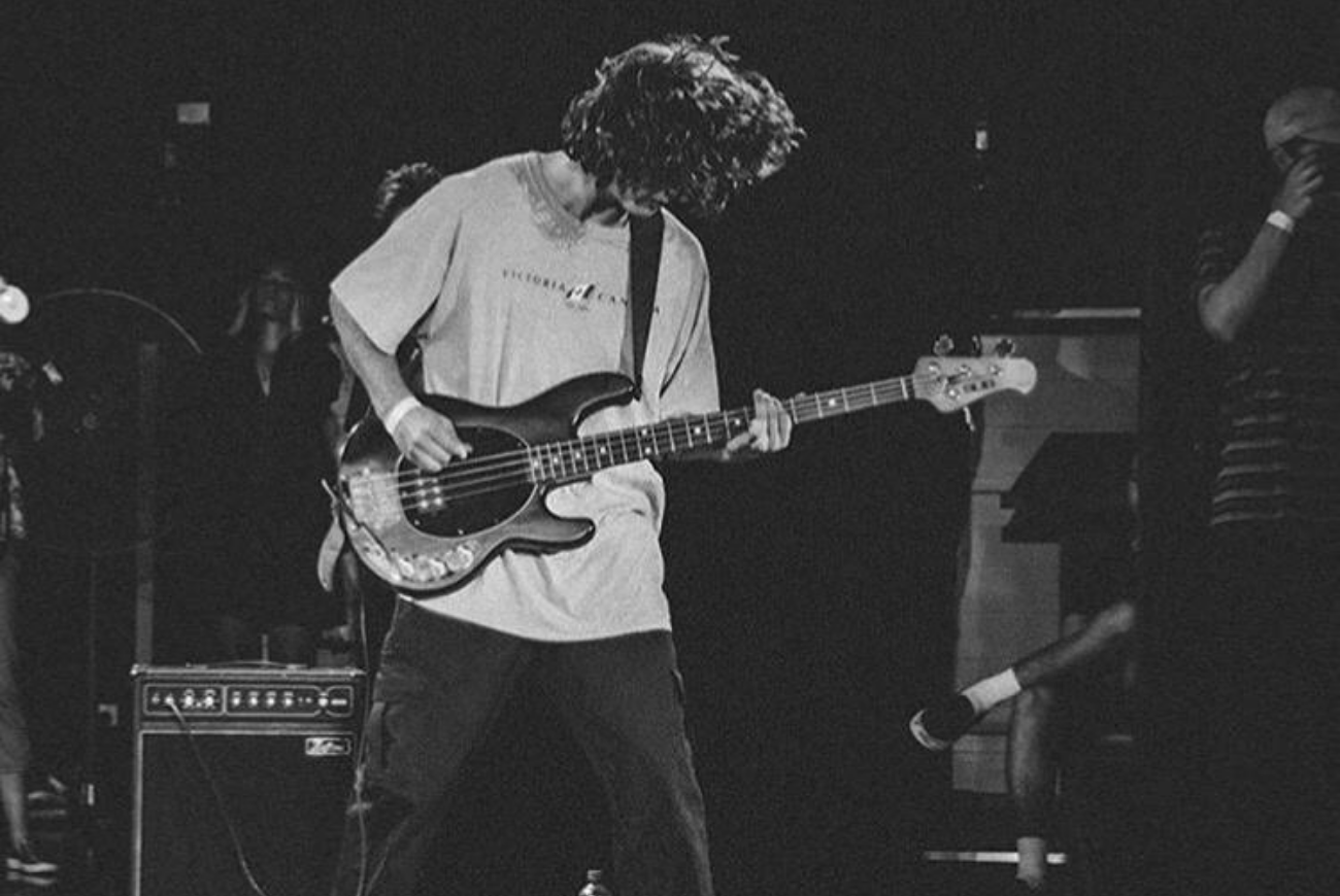 Meet Wyle. Black and white photograph of Wyle playing the electric guitar in his band.