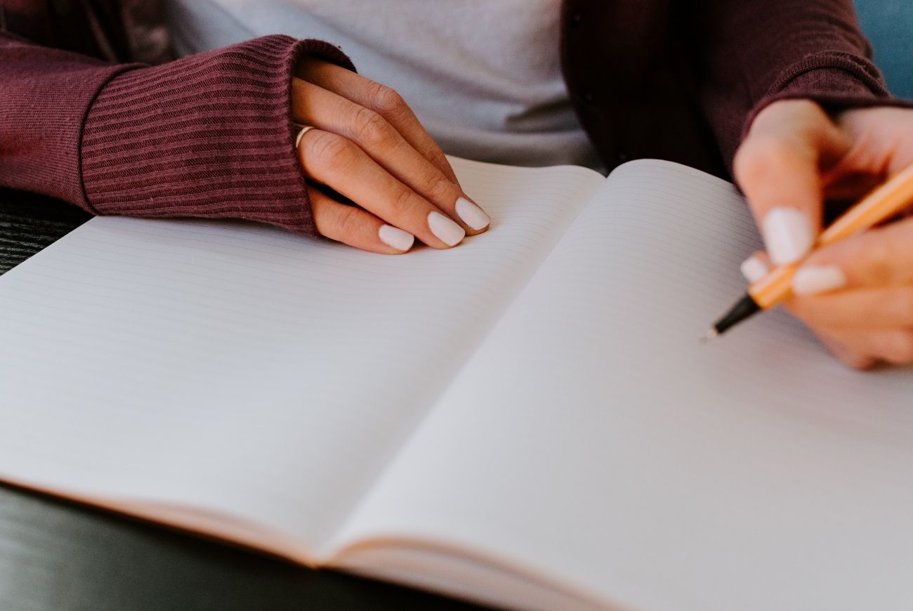 Teaching kids to set goals with girl writing note in note book.