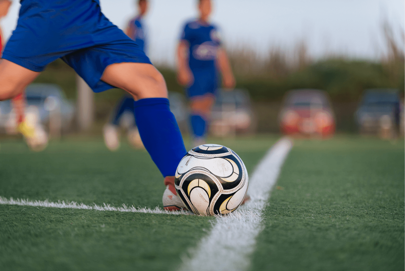 How to encourage kids to exercise. Close up image of boy kicking soccer ball on field.