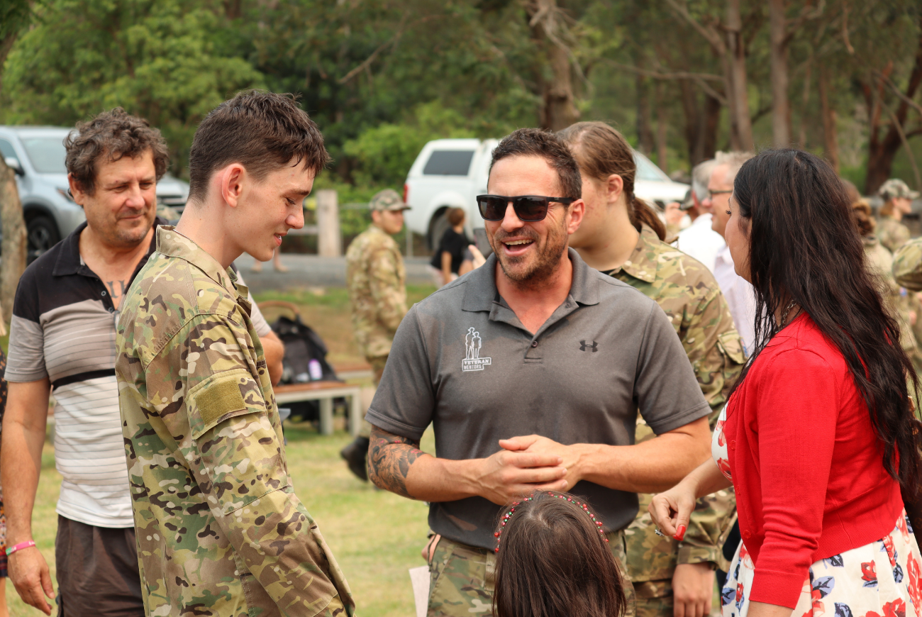 boy wearing army uniform smiling with parent and veteran mentor